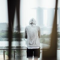 一位穿深色卫衣的男编辑深夜伏案校对稿件，台灯下摊着打印出来的看球直播常见问题清单，纸边写满批注